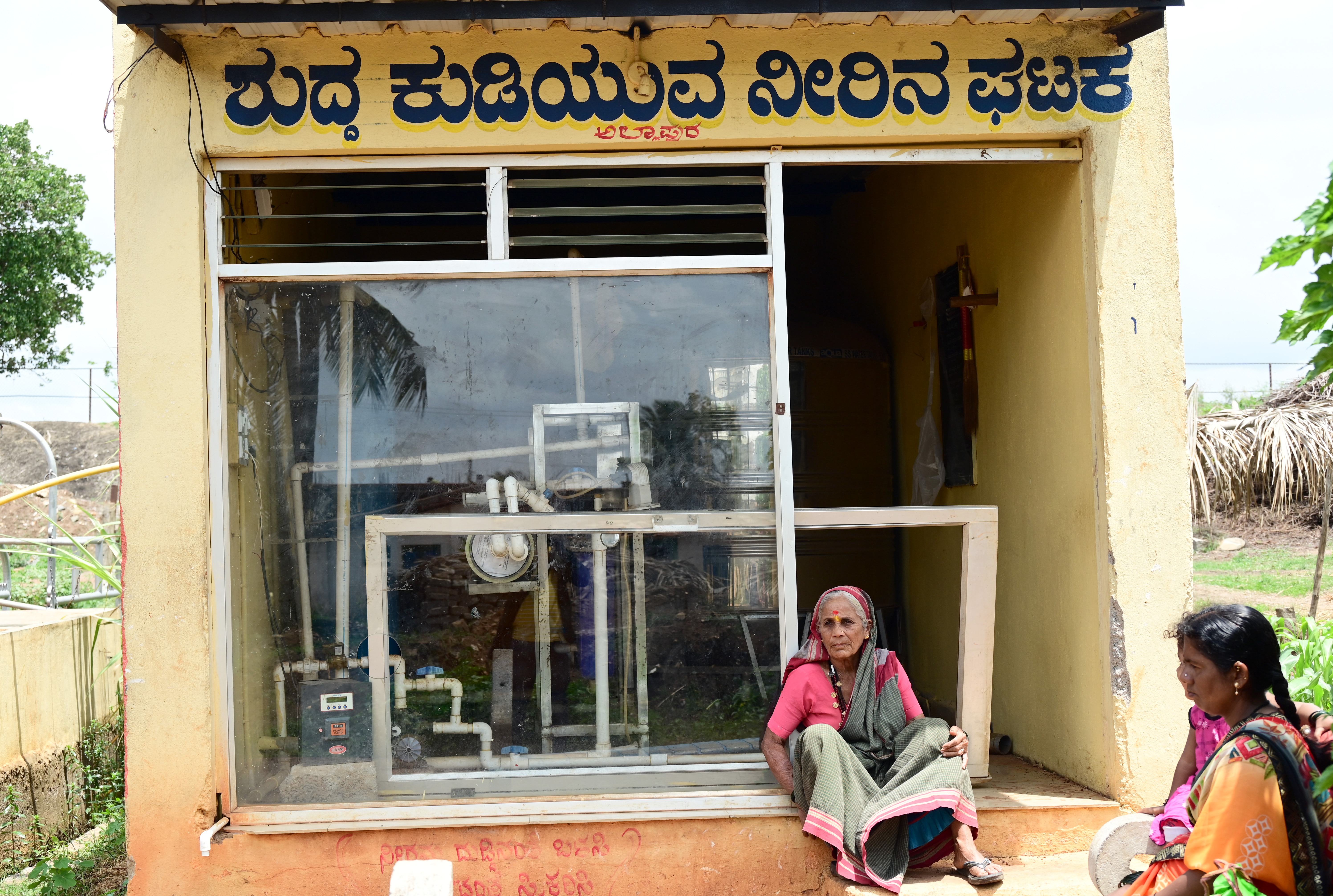 ಕುಂದಗೋಳ ತಾಲ್ಲೂಕಿನ ಅಲ್ಲಾಪುರದಲ್ಲಿ ಸ್ಥಗಿತಗೊಂಡ ಕುಡಿಯುವ ನೀರಿನ ಘಟಕದ ಎದುರು ಬಸ್ಗಾಗಿ ಕಾದು ಕುಳಿತಿರುವ ಮಹಿಳೆಯರು –ಚಿತ್ರ–ಗೋವಿಂದರಾಜ ಜವಳಿ