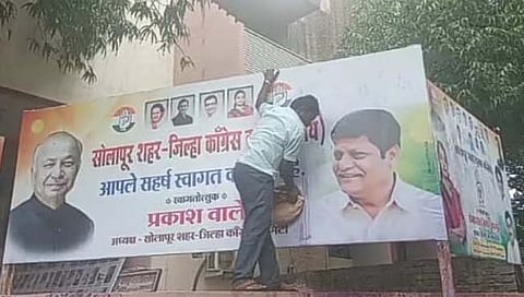 सोलापूर शहरातील काँग्रेस भवनाच्या बाहेरील बॅनरवर फेकण्यात आलेली शाई साफ करताना कर्मचारी.