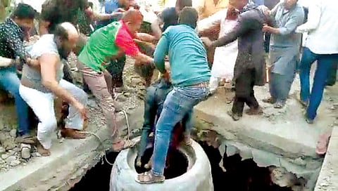 सोलापूर : चेंबरमध्ये पडलेल्या मजुराला बाहेर काढताना नागरिक.