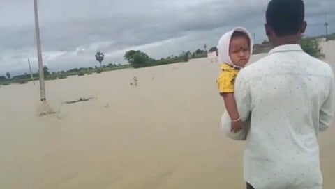 तापाने फणफणणाऱ्या मुलाला घेऊन बापाने काढली पुरातून वाट