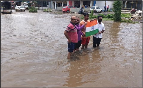 पाण्यात उभे राहून तिरंगा दाखवून पालिका प्रशासनाचा निषेध करताना व्यावसायिक.