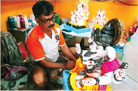 गणेशमूर्तीवर रंगकामाचा शेवटचा हात फिरवताना कलाकार.