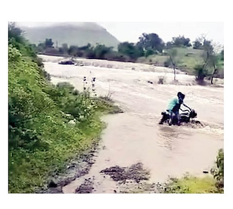 बेल्हे (गुळुंचवाडी) येथील गणेशनगर शिवारात ओढ्याच्या पुरात मोटारसायकल घालताना तरुण. (छाया : सुरेश भुजबळ)