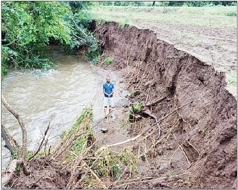 ओढ्यालगतची वाहून गेलेली जमीन दाखविताना शेतकरी.