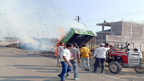 नामपूर : नामपूर-मालेगाव रस्त्यावर वीजतारांच्या घर्षणाने पेटलेल्या चार्याला ट्रॅक्टर ट्रॉलीपासून वेगळे करताना नागरिक. (छाया : विनोद पाटील)