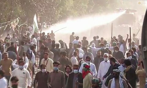 इम्रान खान यांच्या लाहोर येथील निवासस्थाना बाहेर जमलेल्या समर्थकांना पांगवितांना पोलीस.