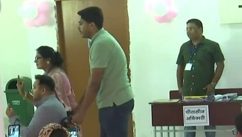 व्हीलचेअरवरून मतदान केल्यानंतर बोटावरील शाई दाखवताना तेजस्वी यादव