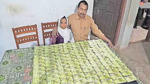 சேமித்து வைத்த இருபது ரூபாய் நோட்டுகளுடன் தந்தையும் மகளும்