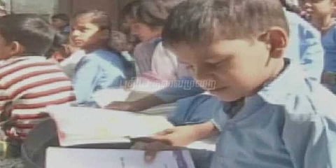 சாலையில் பாடம் படித்த பள்ளி மாணவர்கள்.