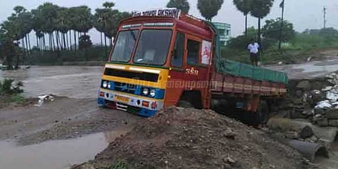காட்டாற்று வெள்ளத்தால் சேதமடைந்த பாலத்தில் தொங்கி நிற்கும் லாரி