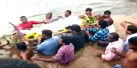 தண்ணீரால் சூழ்ந்த சுடுகாடு பாதை: சடலத்தை கயிறு கட்டி இழுத்துச் செல்லும் அவலம்