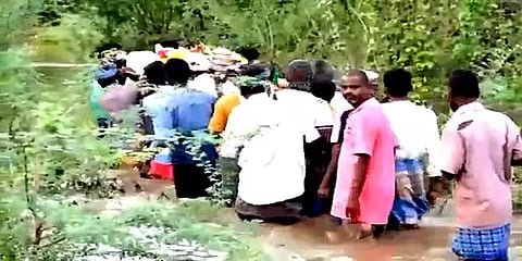 சாலை வசதி இல்லை: வெள்ள நீரில் இறந்தவரின் சடலத்தை கயிறுகட்டி எடுத்துச் செல்லும் அவலம்