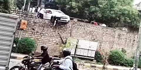 சாலை தடுப்பில் மோதி அந்தரத்தில் தொங்கும் கார் - வாகன ஓட்டிகள் அச்சம்