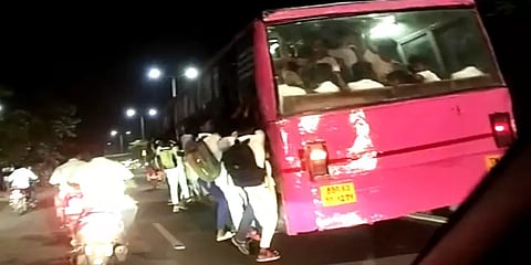 கால்கள் தரையில் உரசியபடி பேருந்தின் படிக்கட்டில் தொங்கிக்கொண்டே பயணிக்கும் மாணவர்கள்!