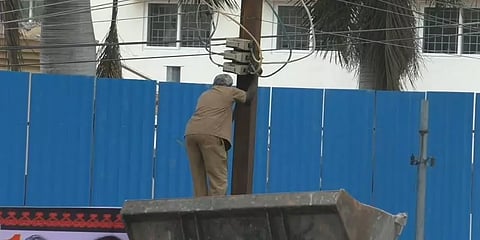 மின்கம்பத்தை ஒட்டி பேனர் வைத்த திமுகவினர்! ஜேசிபி உதவியால் கம்பத்தில் ஏறிய மின் ஊழியர்!