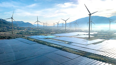 Solar farms and wind turbines operating across a mountainous renewable energy landscape under bright daylight.