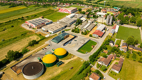 Aerial view of a biogas and industrial renewable energy facility surrounded by agricultural land and rural settlements.