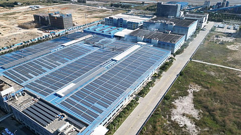 Aerial view of an industrial solar manufacturing complex with rooftop solar panels and large production facilities.