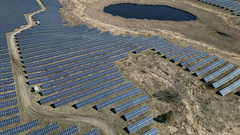 Aerial view of a utility-scale solar farm with extensive photovoltaic panel arrays across open land.
