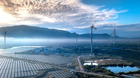 Utility-scale solar panels and wind turbines operating together at a hybrid renewable energy project.