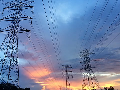 Electricity transmission towers and high-voltage power lines at sunset.