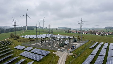 Electrical substation with solar panels and wind turbines.
