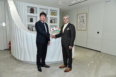 Representatives of Sumitomo Corporation and Hero Future Energies standing together and shaking hands at a signing ceremony, with Japanese and Indian flags displayed between them.