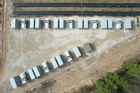 Aerial photograph showing rows of battery energy storage containers on a cleared site beside solar panel arrays at European Energy’s Anykščiai facility in Lithuania.