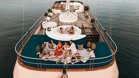 Guests enjoy a relaxed picnic and champagne on the bow of a luxury yacht