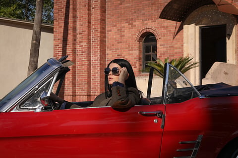 Woman wearing oversized Theian diamond sunglasses in a red convertible