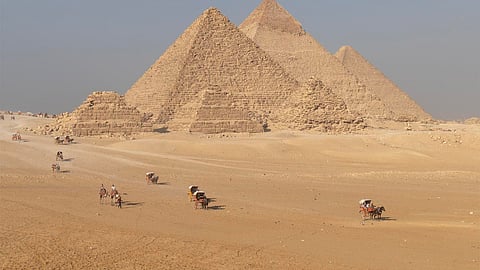 Timeless Caravans Pass the Great Pyramids on a Hazy Afternoon in Giza