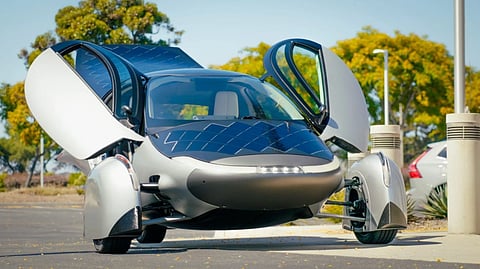 Aptera solar EV with butterfly doors open in parking lot