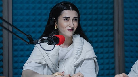 Woman podcasting in soundproof studio booth with blue foam walls