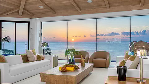 Sunset view from oceanfront living room with warm neutral interiors
