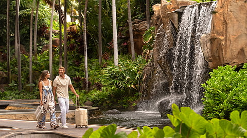 Couple walking by waterfall in tropical resort garden