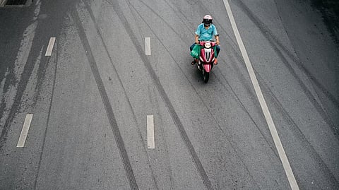 Motorcyclist Rides Alone on Wet Urban Road with Tire Marks