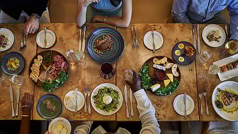 Guests enjoy shared gourmet plates and fine wine at an elegant dining table