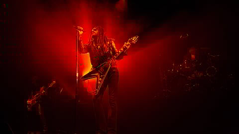 Lenny Kravitz performing live on stage under dramatic red lighting