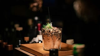 Craft tequila cocktail garnished with herbs and spices on wooden tray