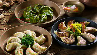 Assorted dumplings in three styles with soup on a rustic table
