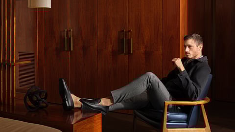 Man seated in a mid-century modern room wearing Magnanni black loafers