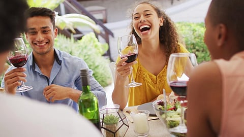 Group of friends laughing and sharing wine at a food-focused event