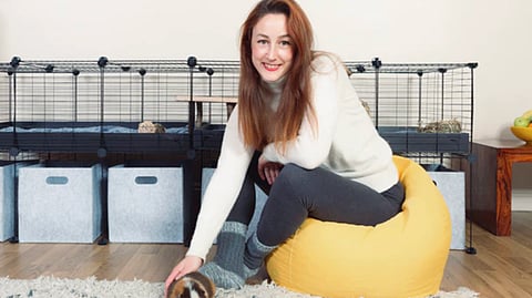 Kavee CEO Clementine Schouteden pets guinea pig in front of cage