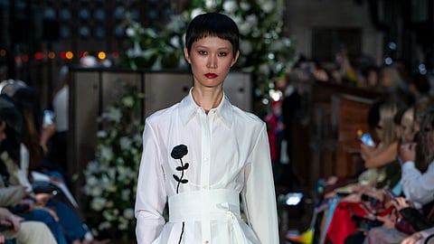 Model in white shirt dress with black floral detail at LFW