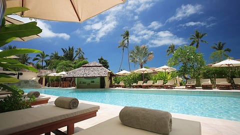 Luxury resort poolside with lounge chairs and tropical palm trees