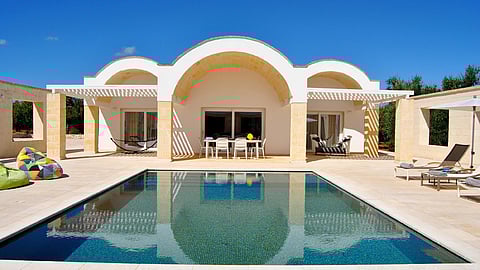 Modern villa with arched design and private pool under a clear blue sky