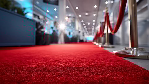 Close-up of a red carpet lined with velvet ropes and spotlights