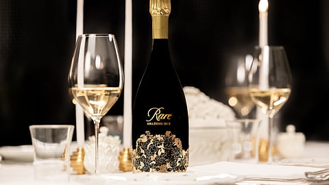 A bottle of Rare Millésime 2013 Champagne and glasses on a dining table