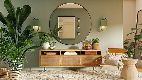 Modern living room with green wall, mirror, plants, and rattan furniture