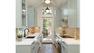 Bright galley kitchen with soft blue cabinetry and natural light